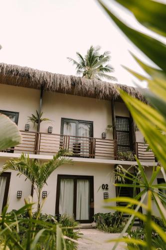 a building with a thatched roof with palm trees at UNLTD Siargao Hotel in General Luna