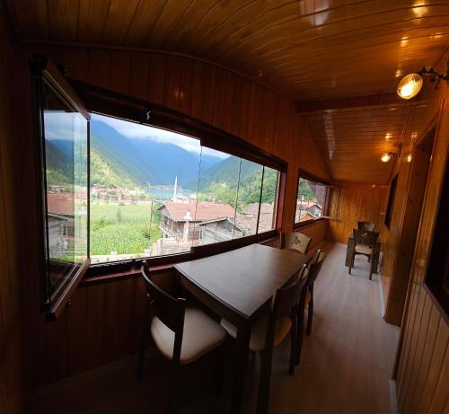 a dining room with a table and chairs and a large window at Uzungöl Sakin Pansiyon in Uzungöl