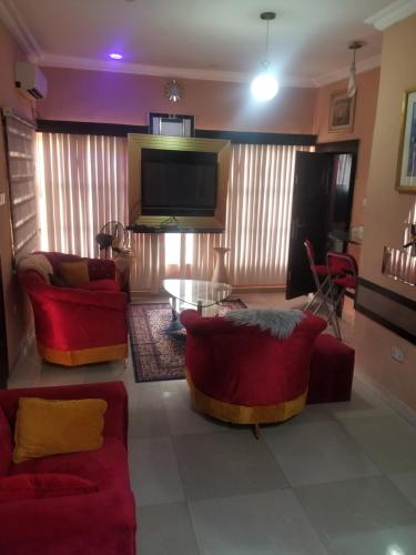 a living room with red furniture and a flat screen tv at Service Apartment in Mama