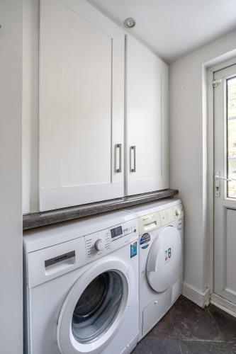 a white laundry room with a washer and dryer at Charming 3BR Victorian House with Parking - 10 Mins to Kingston in Kingston upon Thames