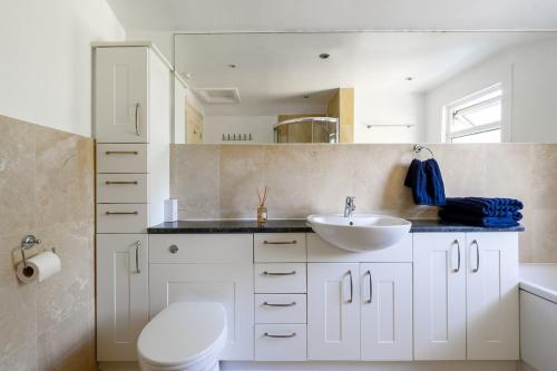 a white bathroom with a sink and a toilet at Charming 3BR Victorian House with Parking - 10 Mins to Kingston in Kingston upon Thames