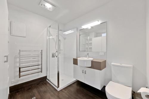 a white bathroom with a shower and a toilet at Port Central No 2 in Port Campbell