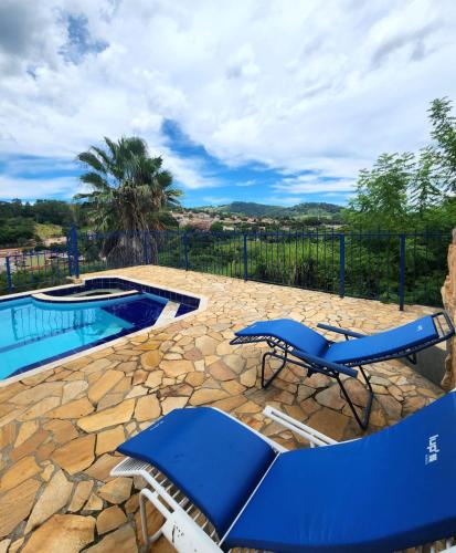 a patio with blue chairs and a swimming pool at Pousada Espaço Cosmos in Águas da Prata