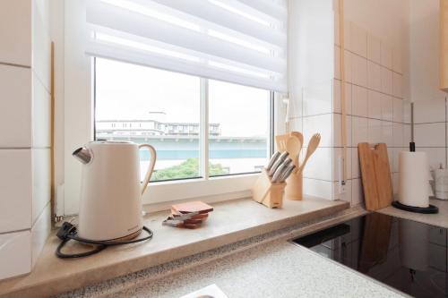 a kitchen counter with a window with a view of the ocean at nJoy! Federsee Getaway - Central - Coffee - Balcony - perfect for business and travel in Bad Buchau