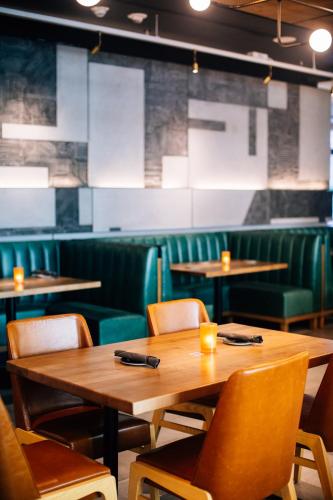 a dining room with wooden tables and green chairs at The Clancy, Autograph Collection in San Francisco