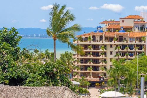 a hotel with a palm tree in front of the ocean at Casa Estela in Puerto Vallarta