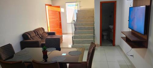 a living room with a dining room table and a television at Lar de charme e tranquilidade em montes Claros in Montes Claros