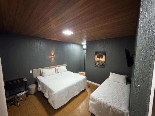 a bedroom with two beds with white sheets at Pousada Recanto Querubins in Paty do Alferes