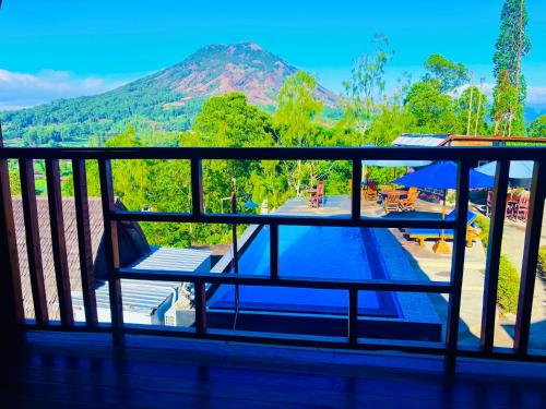 a balcony with a view of a pool and a mountain at Bali Cottages Lake View in Kintamani