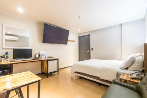 a hotel room with a bed and a desk with a television at illuwa M in Seoul