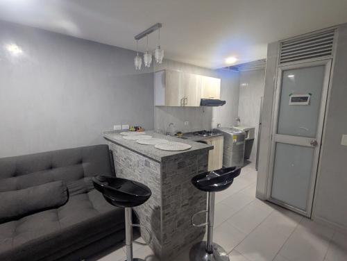 a kitchen with a couch and a counter with stools at Your home away from home in Girardot in Girardot