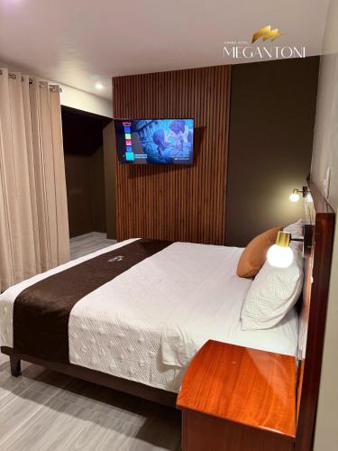 a bedroom with a bed with a tv on a wall at Grand Hotel Megantoni in Quillabamba