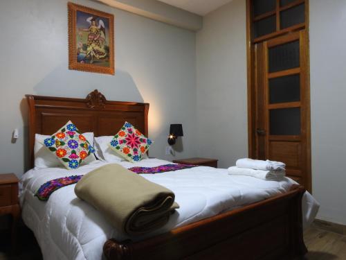 a bedroom with a bed with white sheets and pillows at Rumi Wasi Inn Ollantaytambo in Ollantaytambo