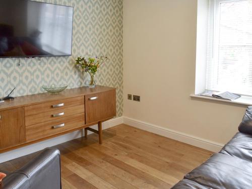 a living room with a couch and a television on a dresser at Mews Cottage in Bridlington