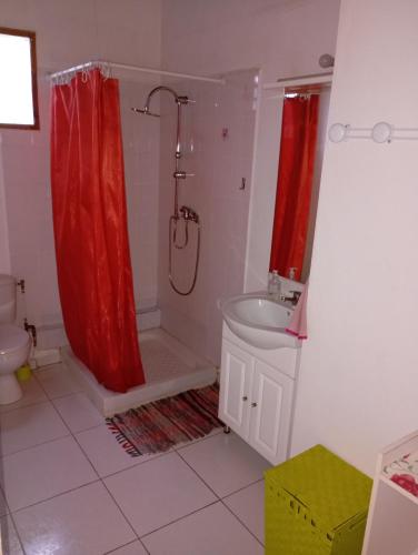 a bathroom with a red shower curtain and a sink at L'Authentique Sikryé in Sainte-Anne