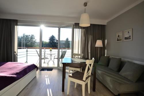 a bedroom with a bed and a table and a couch at Darłówko Apartament Morski in Darłówko