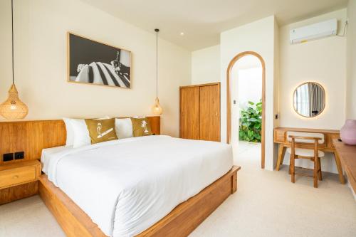 a bedroom with a large white bed and a desk at Kuta Beach Villas by Great Bali Villas in Badung