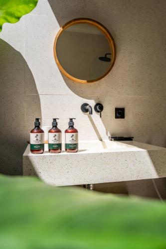 a bathroom sink with three bottles of soap and a mirror at Kuta Beach Villas by Great Bali Villas in Badung