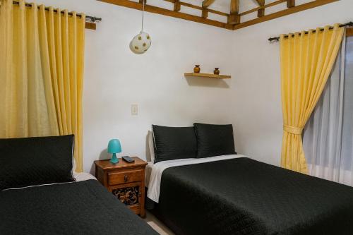 a bedroom with two beds and yellow curtains at Cabaña familiar con 3 dormitorios y baños privados in Villa de Leyva