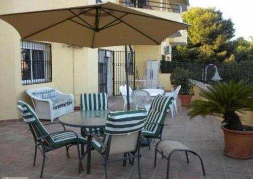 ベナルマデナにあるPuerto marina con gran terrazaのテーブルと椅子と傘のあるパティオ