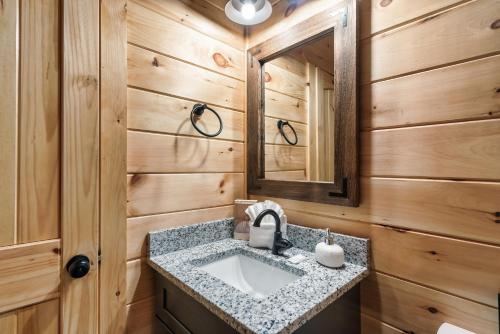 ein Badezimmer mit Waschbecken und Spiegel in der Unterkunft Brand New Cabin close to PForge and GBurg in Sevierville