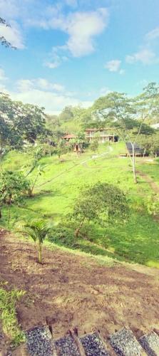 a field of grass with trees and a house in the background at Hospedaje encanto Moniquireño in Moniquirá
