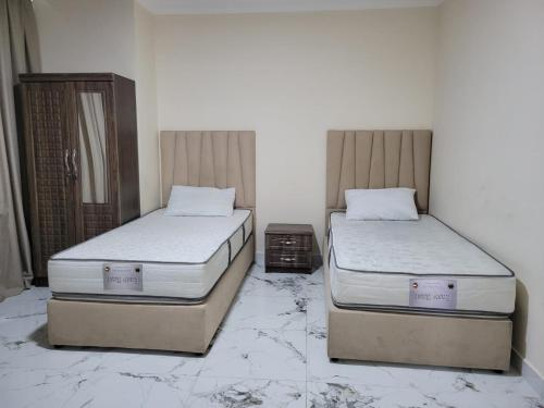 two beds sitting in a room with marble floors at Everest vibes in Abu Dhabi