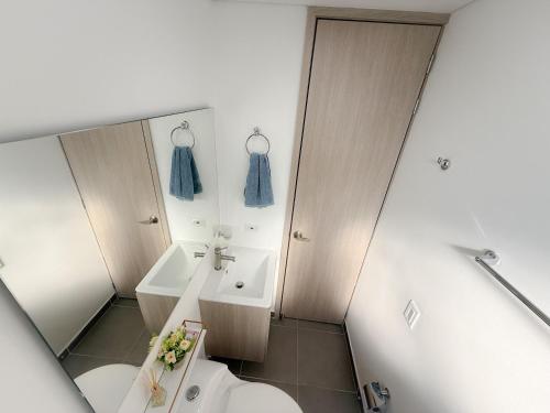 Un baño con lavabo, inodoro y espejo. en Apartamento con vista a la montaña, piscina y gym, en Sabaneta