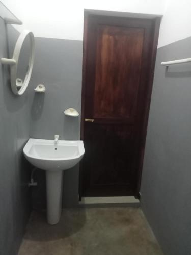 a bathroom with a sink and a wooden door at Piumi House in Hiriketiya