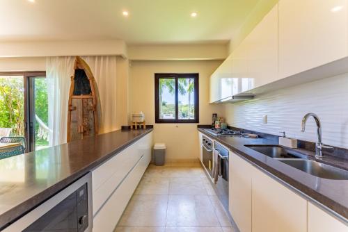 a kitchen with white cabinets and a sink at Luxury Ground Floor MarinaView-Pool-Gym-Paddleboard in Puerto Aventuras
