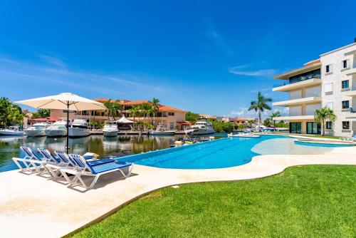 a swimming pool with two chairs and a building at Luxury Ground Floor MarinaView-Pool-Gym-Paddleboard in Puerto Aventuras