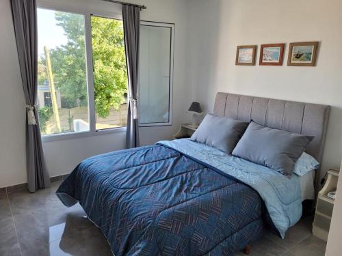 a bedroom with a bed with a blue comforter and a window at Rincon de Mayo in Tandil