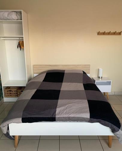 a bedroom with a black and gray comforter on a bed at Meublé bord de Mer in Gravelines