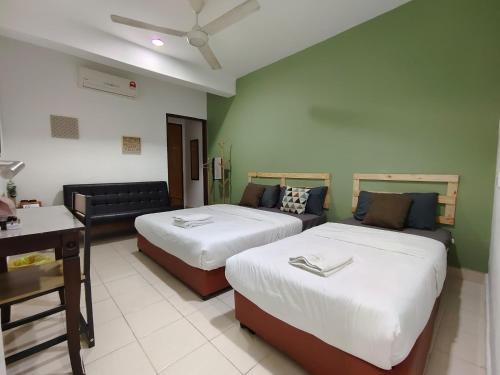 a hotel room with two beds and a couch at Suite Us Guesthouse Kubang Kerian in Kota Bharu