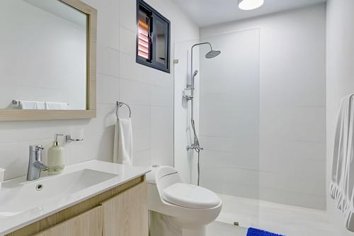 a white bathroom with a toilet and a shower at Caribbean Beachfront Living, Apartment in Juan Dolio