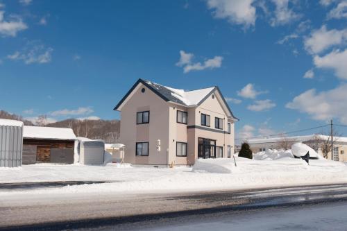a white house with snow on the ground at Rusutu,Ski&Family Lodge 66 in Kimobetsu