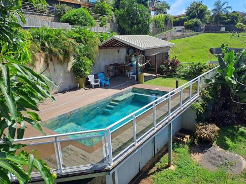 a swimming pool with a wooden deck next to a house at Taapuna Guesthouse family in Punaauia