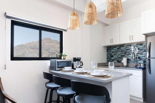 a kitchen with a table with chairs and a microwave at Vista Pedregal-Modern Vacation Apartment Walk to Marina & Beaches in Cabo San Lucas