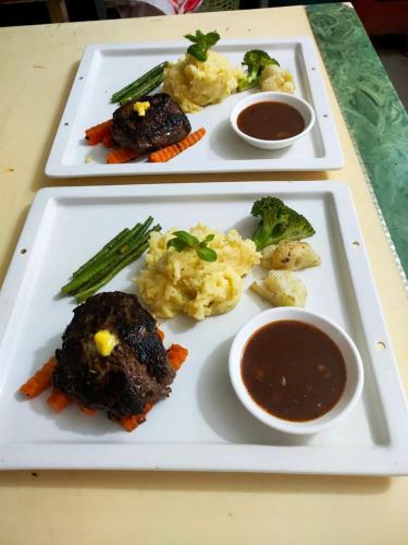two plates of food with meat and vegetables and dipping sauces at SELA Bungalow and Italian Restaurant in Koh Rong