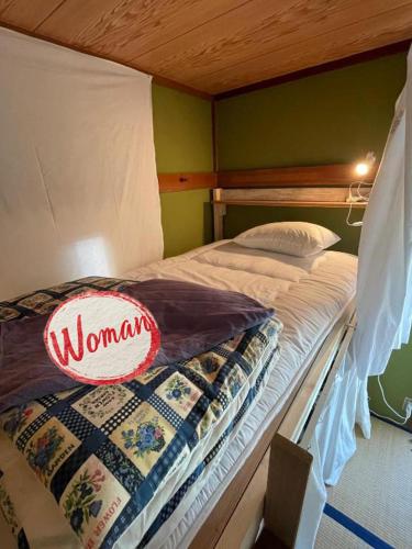 a bedroom with a bed with a woman sign on it at ゲストハウス千倉のおへそ in Chikura