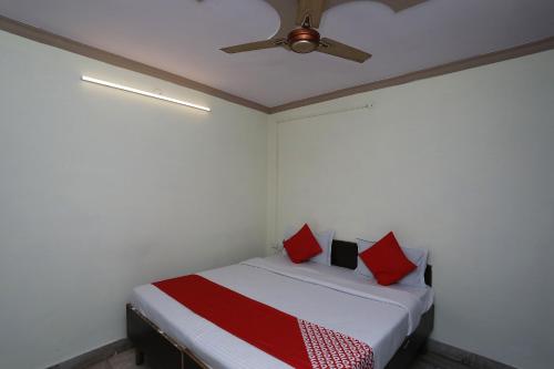 a bedroom with a bed with red pillows and a ceiling fan at Hotel O Vanshika in Agra