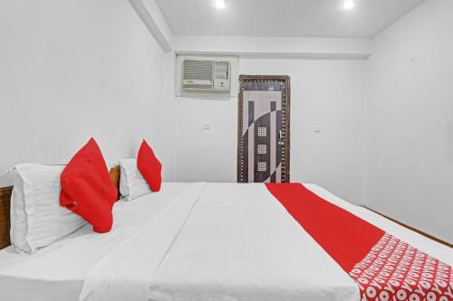 a bedroom with a white bed with red pillows at ALX Townhouse in Indirapuram