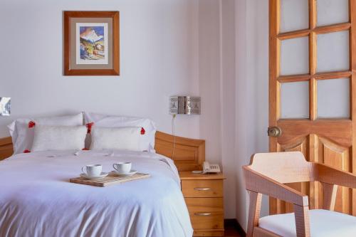 a bedroom with a bed with two cups on a tray at Maimara Hotel in Huaraz