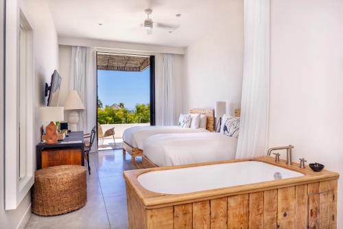 a bathroom with a tub and a bedroom with a bed at Hotel El Ganzo - Adults Only in San José del Cabo