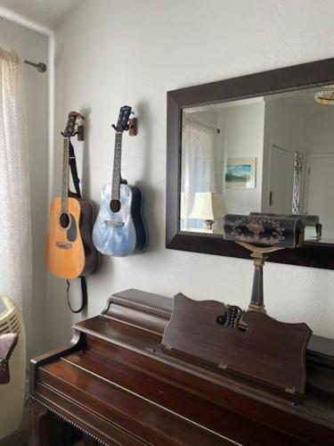 two guitars hanging on a wall next to a mirror at Sunny and Spacious, Hottub, Piano, Guitars, Fenced Yard, Pets Welcome, LGBT Friendly in Westminster