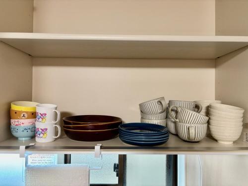 a shelf with bowls and plates on it at 古民家ｓｔｙｌｅ富山駅北 in Toyama