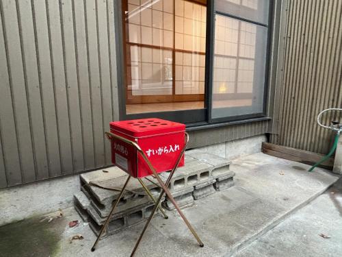 a red stool sitting in front of a window at 古民家ｓｔｙｌｅ富山駅北 in Toyama