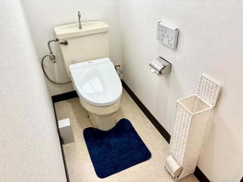 a bathroom with a toilet with a blue rug at 古民家ｓｔｙｌｅ富山駅北 in Toyama