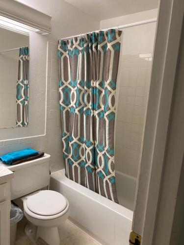 a bathroom with a toilet and a shower curtain at Sunny and Spacious, Hottub, Piano, Guitars, Fenced Yard, Pets Welcome, LGBT Friendly in Westminster