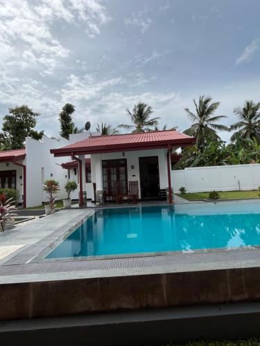 a villa with a swimming pool in front of a house at Serene Retreat Udawalawa in Udawalawe